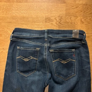 Mörkblå Replay jeans med broderade fickor - Säljer ett par mörkblå jeans från Replay med snygga broderade detaljer på bakfickorna och klassisk Replay-logga. Jeansen har raka ben och normal passform, tillverkade i slitstarkt denim. Perfekta för dig som gillar stilrena och tidlösa jeans.