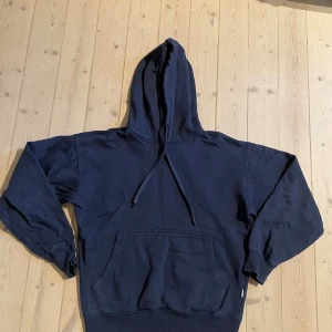  Hoodie mörkblå  - Pris kan diskuteras, skriv för mer bilder! En enkel och stilren mörkblå hoodie med stor huva och dragsnören. Tröjan har en klassisk känguruficka framtill och ribbade muddar vid ärmslut och nederkant. Perfekt för chill dagar eller när du vill ha en avslappnad look.
