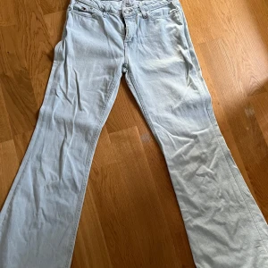 Ljusblå bootcut jeans Tommy Jeans - Snygga ljusblå jeans från Tommy Jeans med klassisk femficksmodell och bootcut-ben. Jeansen har normal midja och är tillverkade i mjukt denimtyg med diskreta Tommy-detaljer på knapp och bakficka. Perfekta för dig som gillar retrovibbar och avslappnad stil.