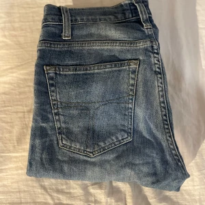 Blåa tiger of sweden jeans - Säljer ett par blå tiger of sweden jeans med snygg tvätt och klassiska fem fickor. Jeansen har slim passform, normal midja och dragkedja. Perfekta för dig som gillar en modern och stilren look. Materialet är mjukt och stretchigt jeans.
