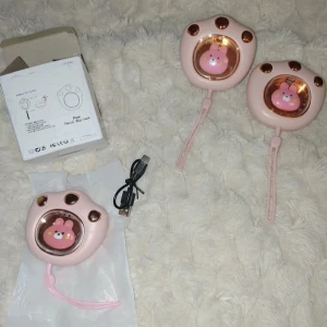Handvärmare - Söta, uppladdningsbara handvärmare i form av rosa tassar med kaninmotiv. Tre stycken i mycket fint skick, inklusive USB-laddkabel och originalförpackning. Perfekt för kalla dagar och enkel att ta med tack vare handledsrem. Priset är för alla men kan köpas separat!