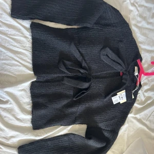 Svart stickad kofta med knytband - Svart stickad kofta från Ginatricot, helt ny med prislapp kvar! 