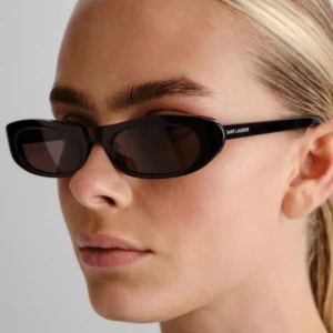 Svarta solglasögon Saint Laurent - Snygga svarta solglasögon från Saint Laurent med klassisk rektangulär form och diskret logga på skalmen. Glasögonen har en stilren look och kommer med originalfodral och putsduk. Perfekta för dig som vill ha en tidlös accessoar med lyxig känsla.