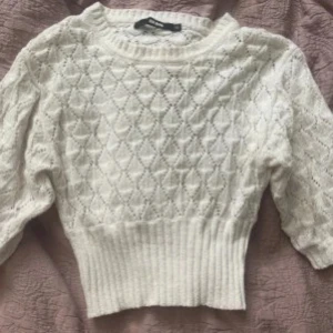 Vit stickad tröja med mönster - Supersöt vit stickad tröja från bik bok med diskret hålmönster och bred ribbad midja. Skriv för fler bilder. Aldrig använd.