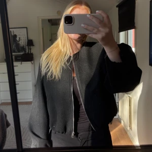 Svart croppad jacka från Zara - Säljer en svart croppad jacka från Zara med dragkedja framtill och diskret rund halsringning. Jackan har ballongärmar och elastisk nederkant för en snygg passform. Har aldrig använt jackan, endast testat på!🖤