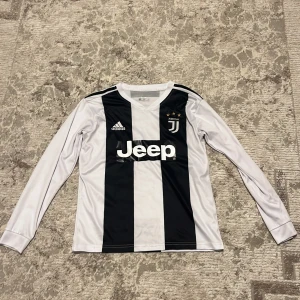 Juventus långärmad Ronaldo tröja #7 - Juventus fotbollströja med Ronaldo 7 på ryggen, tillverkad av Adidas. Klassisk svartvit randig design med Jeep-logga på bröstet och Juventus-emblem med tre stjärnor. Långärmad modell i lätt och glansigt material, perfekt för dig som älskar fotboll och Cristiano Ronaldo. Ni får välja pris ni vill ha den för😄.