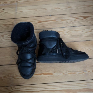 Svarta vinterboots från Inuikii - Säljer ett par svarta vinterboots från Inuikii med snörning och rund tå. Skorna är fodrade med mjukt material på insidan och har en platt sula. Har inget att anmärka på, innan jag skickar/möts upp bordtar jag naturligtvis upp fluffet på insidan 