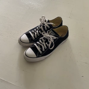 Svarta Converse All Star sneakers - Klassiska svarta Converse All Star sneakers i bra kvalité  med vit tå och vita snören. Lågt skaft, tydliga kontrastsömmar och platt sula. 