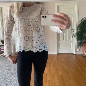 Vit Zara blus med fint mönster - Superfin vit blus i bomull med hålmönster. Blusen har lång ärm, rund halsringning och vågig kant nertill. Perfekt för dig som gillar trendig och söt stil. Storlek S!