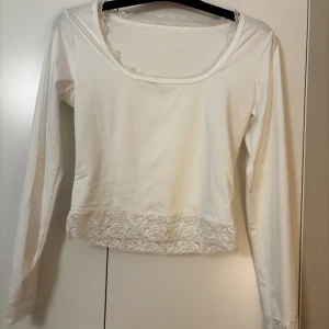 Vit långärmad topp med spets från SHEIN - Säljer en vit långärmad topp från SHEIN i mjuk polyesterblandning. Toppen har rundad urringning och fina spetsdetaljer vid halsringning, ärmslut och nederkant. Perfekt för dig som gillar romantiska och feminina detaljer.