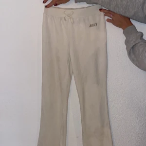 Vita mjukisbyxor Juicy Couture 8/10 - Supermysiga vita mjukisbyxor från Juicy Couture med broderad logga framtill. Byxorna har hög midja, ribbad linning och söt rosett framtill. Tillverkade i en mjuk mix av bomull och polyester för extra komfort.