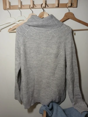 Grå ribbad polotröja - Mysig grå polotröja med ribbad struktur och hög krage. Perfekt för kyliga dagar och enkel att matcha med jeans eller kjol. 