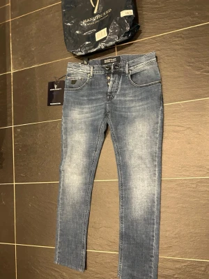 Blå skinny jeans från Handpicked - Säljer ett par blå skinny jeans från Handpicked Moser Project. Jeansen har en snygg tvätt med ljusa partier, klassiska fem fickor och silverfärgade knappar. Materialet är stretchigt jeans och passformen är tight hela vägen ner.