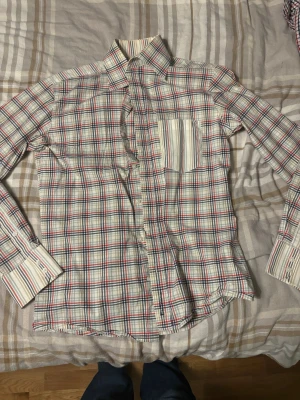 Rutig skjorta från Ben Sherman M - Säljer en vintage Ben Sherman skjorta i storlek M. Skjortan har ett klassiskt rutigt mönster i vitt, blått, rött och beige. Den har långa ärmar, bröstficka med randigt tyg och knappar framtill. Tillverkad i mjuk bomull, perfekt för en chill och stilren look.