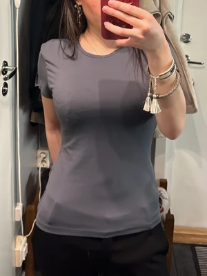 Mörkgrå tight t-shirt - Säljer en enkel och stilren mörkgrå t-shirt med tight passform. T-shirten har rund halsringning och korta ärmar. Perfekt basplagg💕