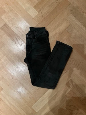 Levis jeans - Säljer ett par svarta snygga jeans med klassisk femficksdesign och smal passform. Jeansen har en mörk tvätt och är tillverkade i stretchigt jeansmaterial för extra komfort. Perfekta till sneakers eller boots.