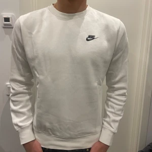 Vit sweatshirt från Nike XS - Säljer en stilren vit sweatshirt från Nike i storlek XS. Tröjan har rund halsringning, diskret Nike-logga på bröstet och är tillverkad i mjuk bomullsmix. Perfekt till jeans eller joggers för en clean look.