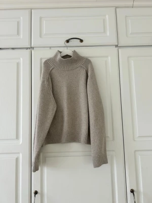 Beige polotröja från H&M, storlek M💖 - Säljer en beige polotröja från H&M i storlek M. Tröjan har en hög, ribbad krage och är stickad med grova muddar vid ärmslut och nederkant. Perfekt för kyliga dagar och har en loose passform som ger en avslappnad vibe 🌟 Köpt på plick men säljer då den inte var min stil! Pris kan diskuteras 