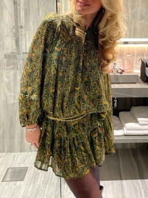 Grön blommig kortklänning med volang - Säljer en grön kortklänning med blommigt mönster och volangdetaljer. Inga defekter  