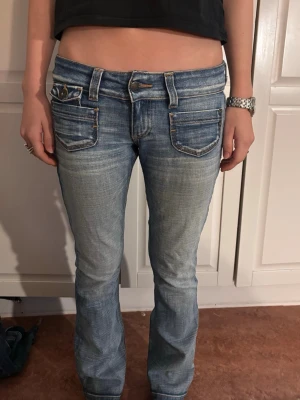 Lågmidjade blå jeans från Only - Säljer ett par lågmidjade blå jeans från Only med slitna detaljer och ljus tvätt. Jeansen är lite flared. Perfekta för en chill och trendig look.