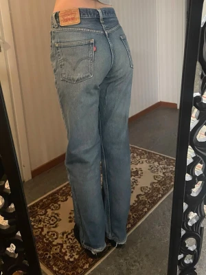 Levi's 550 blå jeans straight fit - Klassiska blå Levi's 550 jeans med straight fit. Jeansen har fem fickor, gylf med dragkedja och den ikoniska läderlappen bak. Tillverkade i slitstarkt bomullstyg med en snygg tvättad look. Något slitna bak vid ankelpartiet, men det tillför bara enligt mig!