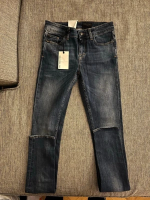 Mörkblå skinny jeans W26 L34 - Säljer ett par mörkblå skinny jeans från Tiger of Sweden  Jeans med snygga slitningar och tvättade detaljer. Klassisk femficksmodell, normalhög midja och stretchigt jeansmaterial för skön passform. Jeansen är helt nya bara testade en gång finns till o med lapp kvar på de.