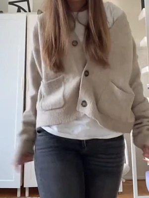 Beige kofta med knappar - Mysig beige kofta med stora knappar framtill och två rejäla fickor. Koftan har en loose passform och är perfekt att slänga på sig över en t-shirt. Tillverkad i ett stickat material som känns både mjukt och avslappnat. Lite nopprig och har nån fläck på ena armen  men inget man tänker på🥰