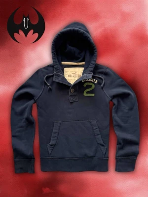 Mörkblå Hollister hoodie med tryck - Mörkblå hoodie med tryck och grön markering på bröstet från Hollister | mycket bra skick | Size M / S | Längd: 65cm Axelbredd: 44cm Armlängd: 70cm | Modell 162cm, 60kg OBS! Modellens längd påverkar inte hoodiens mått!