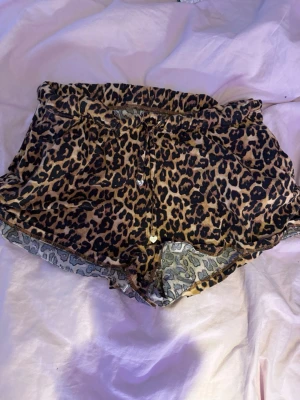 Leopardmönstrade shorts från Censored - Snygga shorts från Censored i leopardmönster med bruna och svarta toner. De har snörning i midjan med små hjärtformade detaljer och är tillverkade i mjuk bomull. Perfekta för dig som vill sticka ut lite extra.
