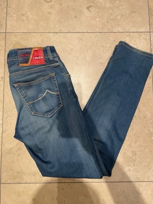  Jacob Cohën, nick - Säljer ett par snygga blå jeans från Jacob Cohën ”nick” i storlek 31. Klassisk femficksmodell med kontrastsömmar och patch i läder bak. Jeansen har normal passform och är tillverkade i mjukt bomullsmaterial med en skön känsla.                 Nypris ca 7000, skriv vid frågor!