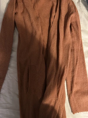 Rosa  stickad väst från XOXO friend - Mysig rosa stickad kofta från XOXO friend i storlek 170. Koftan har en öppen design utan knappar, två fickor framtill och är gjord i ett mjukt stickat material. Perfekt för lager-på-lager och chill vibes.