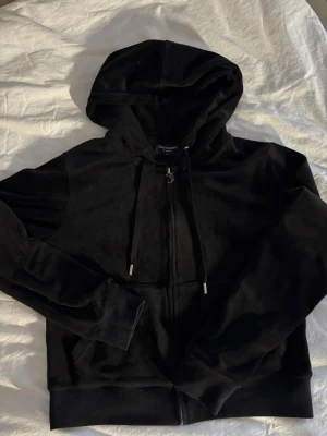 Svarta mjukisbyxor från Juicy Couture - Säljer ett par svarta mjukisbyxor från Juicy Couture i mjuk sammet. raka ben och två fickor bak med lock och silverfärgade knappar. Perfekta för en chill och avslappnad look.