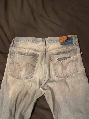 Levi's 517 ljusblå bootcut jeans - Ljusblå Levi's 517 jeans med klassisk bootcut passform. Low/mid rise midja.  Levi's patch bak och den ikoniska röda Levi's-taggen. Tillverkade i slitstarkt jeansmaterial av bomull. Snyggt slitna detaljer!!  Innerbenslängd:77cm Midjemått rakt över:39cm