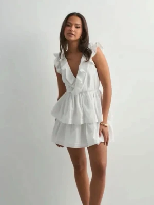 Vit volangklänning med öppen rygg - Supersöt vit kortklänning med volanger och djup v-ringning samt öppen i ryggen. Perfekt för sommarens alla tillfällen och ger en fräsch och luftig känsla. Storlek xs men passar även s🩷Använd 1 gång.