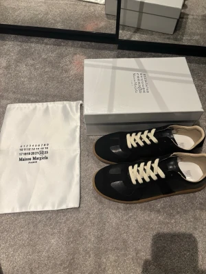 Maison Margiela svarta gats - Säljer ett par svarta sneakers från Maison Margiela. Kommer med original dustbag och låda. Knappt använda! Strlk 44 men sitter lite mindre