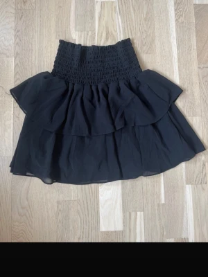 Svart minikjol med volang - I väldigt bra skick då den knappt är använd. 