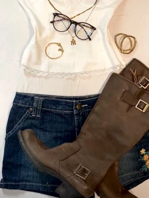 Blommiga jeansshorts från Bijou - Säljer ett par mörkblå jeansshorts från Bijou med broderade blommor i rött, gult och grönt både fram och bak. Klassisk femficksmodell med knapp och dragkedja. Perfekta till sommaren för en chill och färgglad look.