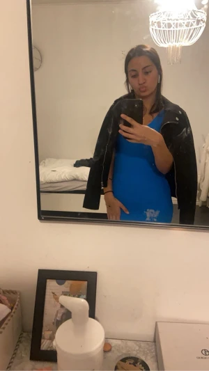 Blå ribbad långklänning med v-ringning - Säljer en snygg blå långklänning med ribbad struktur och v-ringad hals. Klänningen är ärmlös och har en slits på sidan som ger en cool touch. Passformen är tight och materialet känns mjukt och stretchigt, perfekt för dig som gillar att sticka ut med färg.