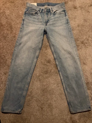 Ljusblå jeans straight fit - Säljer ett par klassiska ljusblå  jeans med rak passform och fem fickor. Jeansen har knappgylf och är tillverkade i slitstarkt bomullsdenim. Perfekt för dig som gillar tidlös och avslappnad stil.