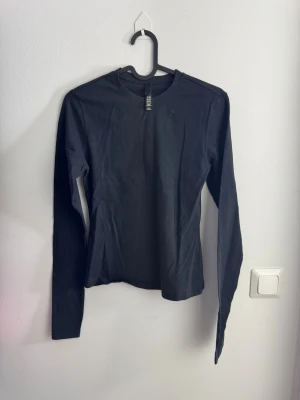 Svart slim fit långärmad topp från SKIMS - Svart långärmad topp från skims i stretchigt bomullsmaterial. Enkel och stilren design med rund halsringning och smal passform. Perfekt att matcha med jeans eller kjol för en clean look. Storlek S.