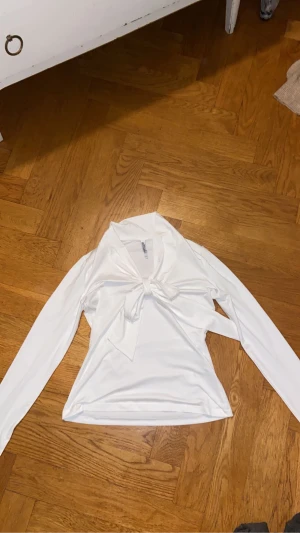 Vit långärmad topp med knyt från Chiara Forthi - Supersnygg vit långärmad topp från Chiara Forthi Milano med knyt framtill. Toppen har en mjuk och stretchig känsla, perfekt för att lyfta din outfit med en clean och fräsch look. Snygg krage och figurnära passform.