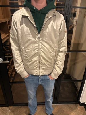 Woolwich Beige bomberjacka  - Säljer en stilren beige bomberjacka från Woolrich. Märkespatch på ärmen och klassisk bomberkrage.  Skön inför höst, vintern och vår! Riktigt bra skick och god passform! Storlek: L pris: 1399kr 