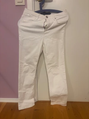 Vita raka jeans  - Snygga vita jeans med klassisk femficksdesign och rak passform. Byxorna har dragkedja och knapp framtill, samt bälteshällor. Perfekta för dig som vill ha en clean och fräsch look. Materialet är jeans och färgen är helt vit.