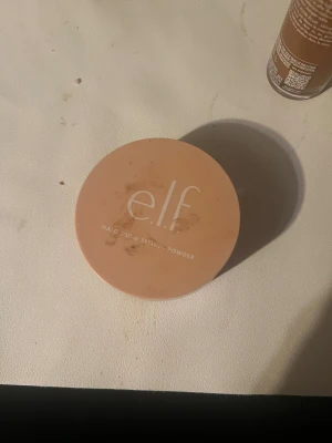 e.l.f. Halo Glow Setting Powder Medium - Säljer ett e.l.f. Halo Glow Setting Powder i färgen Medium. Kommer i en rund burk med persikofärgat lock och transparent underdel. Perfekt för att fixera din makeup och ge en snygg glow. Lätt och silkeslen formula som smälter in i huden.