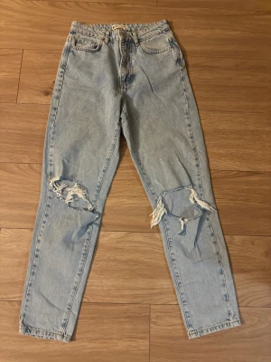 Ljusblå ripped jeans från Perfect Jeans - Snygga ljusblå jeans med hög midja och raka ben från Perfect Jeans. Jeansen har slitna detaljer och stora hål vid knäna. Använt Max 2 gånger