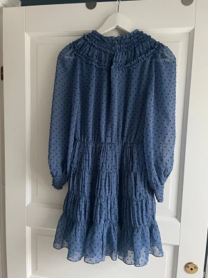 Blå prickig volangklänning Sandro Paris - Supersöt blå kortklänning från Sandro Paris med svarta prickar, i väldigt bra skick använd några fåtal gånger, köpt för 2000