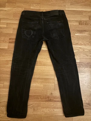 Nudie Jeans - Gritty Jackson 30/30 - Säljer dessa fina jeansen från Nudie Jeans i svart för bara 399. Byxorna har en snygg, unik färg och modellen sitter slim/straight. Dem är i väldigt fint skick och finns inte mycket tecken på användning.  Dem är redo att hitta ett nytt hem! Fråga gärna om ni vill ha fler bilder eller mer informationen 
