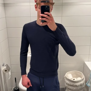 Mörkblå merinotröja från Riley - Snygg mörkblå rundhalsad tröja från Riley i mjuk och tunn merinoull. Klassisk och stilren passform med långa ärmar och ribbade muddar vid ärmslut och nederkant. Kostar 899 kr ny och jag på bilden är 187cm, men som ni ser är den lite liten så skulle säga att den passar dig mellan 180-170. Hör gärna av er om prisförslag och frågor 