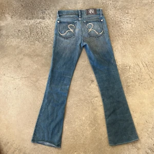 Rock & Republic blå bootcut jeans - Jätte snygga blå jeans från Rock & Republic som jag säljer eftersom de tyvärr är för små för mig. Jeansen är låg midjade, bootcut och har skitsnygga bakfickor med broderade R och rhinestones. 