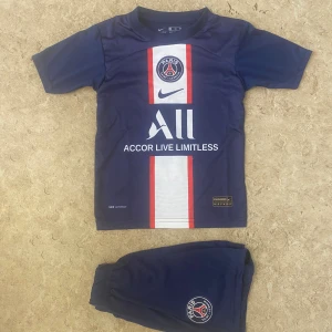 PSG Mbappé matchtröja Nike blå - Paris Saint-Germain fotbollströja med Mbappé och nummer 7 på ryggen. Tröjan är marinblå med vit och röd vertikal rand på framsidan, PSG-logga och sponsortryck. Kortärmad och tillverkad i lätt polyester, perfekt för träning eller match.